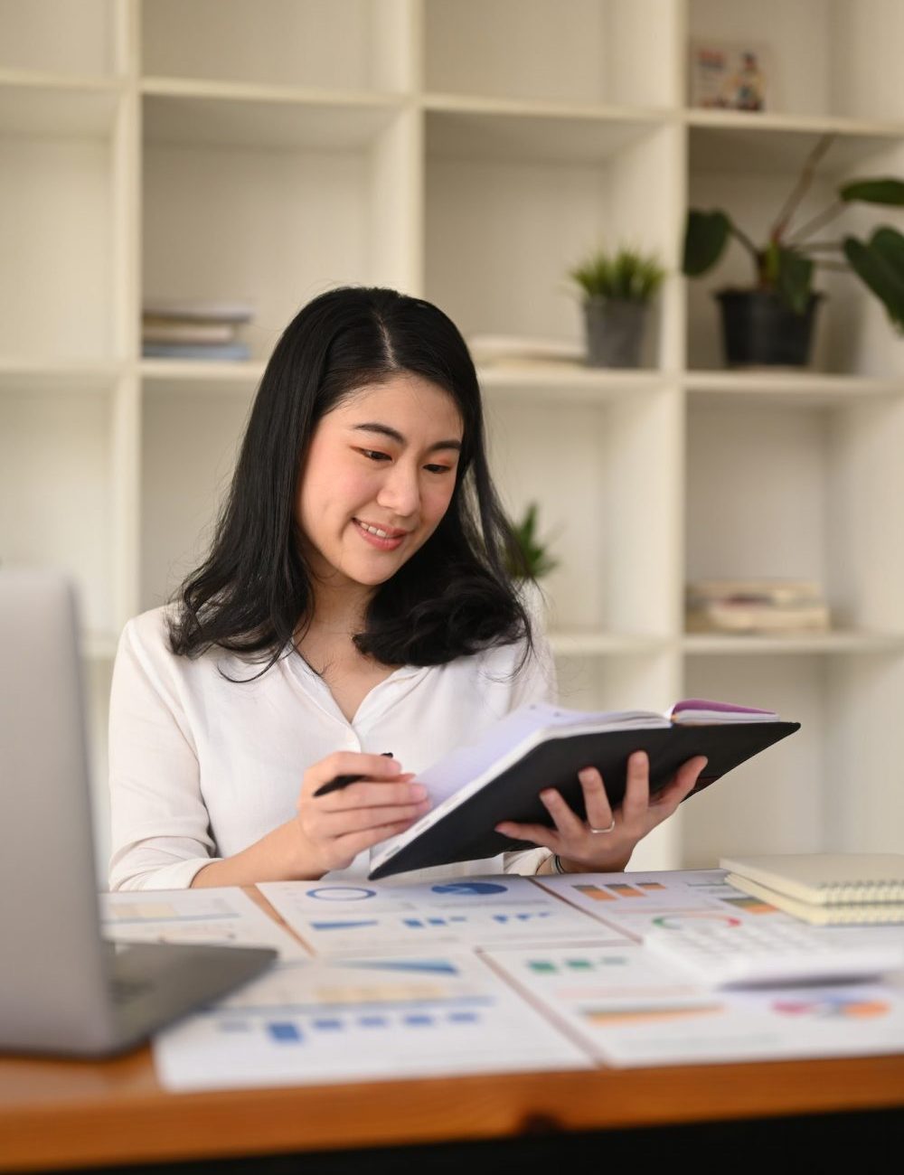 attractive-young-businesswoman-working-with-laptop-and-document-at-corporate-office--e1670796374357.jpg